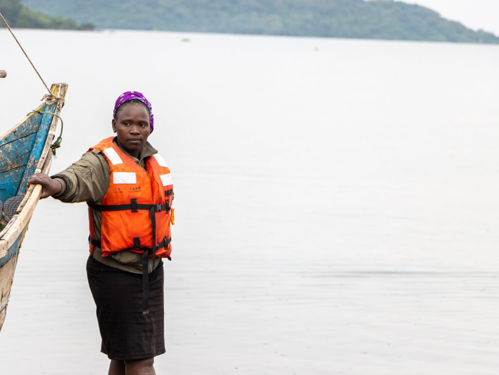 A woman fish farmer in a life vest beside her boat